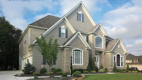 Decorative scallop siding on gables of mixed material facade modern home.