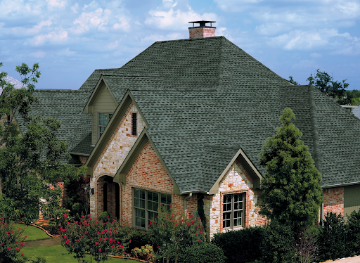 Large home with light pink brick facade and a Hunter Green Timberline HD asphalt shingle roof.