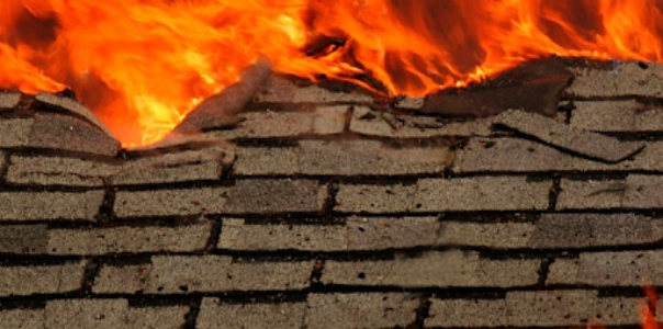An asphalt shingled roof covered in orange flames.