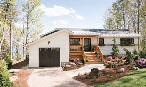 White house with dark garage door, dark windows, and natural wood color staircase to the porch.