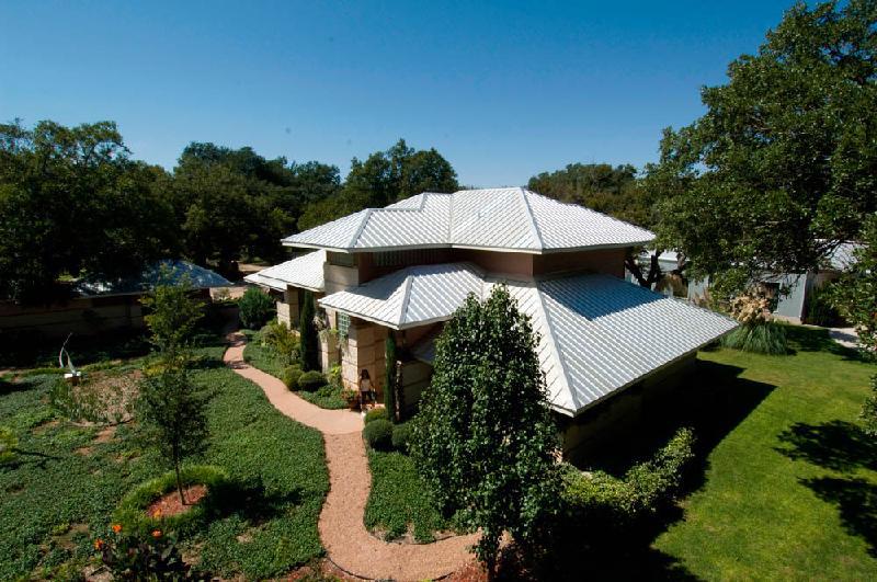 A large two story home surrounded by a lush garden with a steel mueller roof.