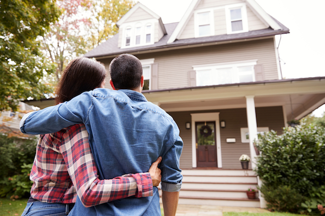 View of couple from the back as they look toward a two-story house