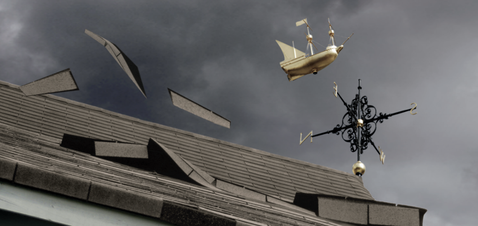 An asphalt shingle roof in the middle of high winds. Several shingles have been torn off.