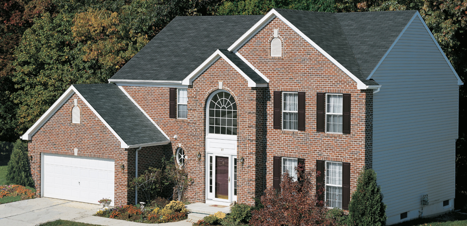 GAF asphalt shingles in charcoal atop a large brick home.